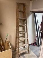 Full view of the 8 foot wooden ladder standing upright against a wall, showing its overall height and structure.