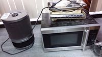 Microwave, kitchen scale, and Amaircare heater sitting on a table with cords visible.