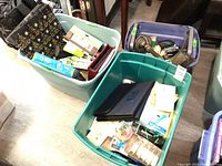 Three plastic bins filled with assorted office supplies such as gift bags, paper pack, highlighters, tape, scissors, and more.
