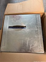 Top view of the portable tile saw showing metal surface with rulers and handle.