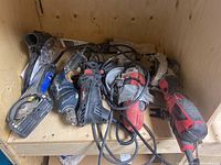 Top view of corded power tools including grinder, drill, circular saw and others in wooden box