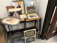 Eight assorted prints and photo displayed on shelves and tables, showing variety of frames and sizes including a prominent oval vintage photo on glass.