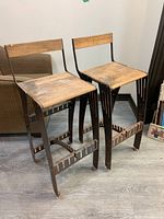 Pair of steampunk style metal frame counter stools with wood seats and backs, showing side and front views.