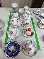 Overhead photo showing nine sets of teacups and saucers in various floral designs and colors.