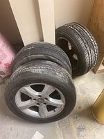 Three Yokohama AVID Envigor tires mounted on BMW alloy rims, shown stacked in a room corner
