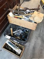 Overview of one wooden box, one plastic bin, and one smaller wooden box filled with tools and hardware.