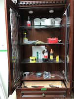 Wooden credenza shelves with various tools including PVC piping, copper coil, tape rolls, hand tools, hardware boxes, and other related items.
