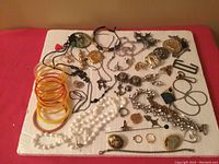 Full lot laid out with various vintage jewelry items including bangles, rings, brooches, necklaces, chains, and bracelets