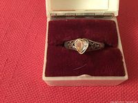 Front view of the sterling silver ring with heart-shaped faceted center stone displayed in red velvet box.