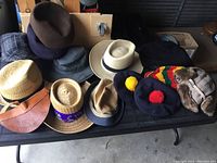 Overview photo of assorted vintage men's hats in various styles and materials arranged on a black table.
