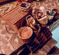 Photo showing a variety of wicker baskets including a large locked wicker basket with lid, several smaller baskets of different shapes and sizes, and wicker organizer baskets with compartments.