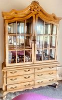 Front view of the entire wooden armoire showing glass paneled top doors, six drawers below, and decorative crown molding.