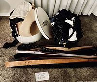 Top-down photo showing knit and straw hats with some belts and purse in the background