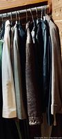 Photo showing six ladies coats on a rack, including beige, brown, black, and gray coats in various styles and materials