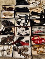 Close-up showing various pairs of women's shoes organized in shoeboxes on carpet. Styles include leather, suede, patent leather in multiple colors: black, white, beige, red, and leopard print.