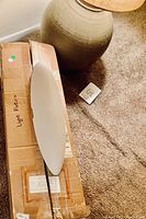 Photo showing the ceramic lamp base and the boxed new light fixture laid on carpet.