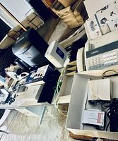 Desk surfaces with fax machine, shredder, speakers, and miscellaneous office supplies scattered on desks