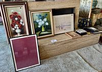 Full view of floral paintings and framed artwork along with frames and photo box arranged on a step
