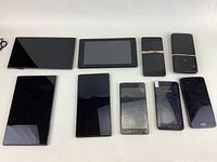 Front view of all 10 devices arranged on a table, including phones and tablets of various sizes and conditions