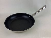 Stainless steel skillet with non-stick interior shown from overhead, good condition with minor wear.