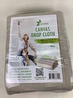 Front packaging of the canvas drop cloth showing brand Green Lifestyle, measurements 12ft width by 15ft length, 8oz thickness, with transactional barcode and some product features.