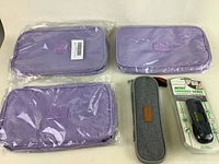 Three purple travel hygiene organizer bags in sealed plastic packaging on display alongside a gray zippered utensil case and a boxed digital luggage scale.