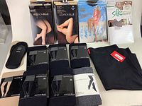 Overview photo showing multiple packages of Addition Elle tights and leggings, a pair of Spanx leggings folded with the red tag, and packaging for Silks tights and Summertime hosiery.