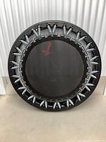 Front view of black rebound trampoline showing the jumping surface with red logo and all silver springs attached to thick padded frame.
