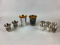 Photo showing all 10 kiddush cups arranged in a row, varying in size and design