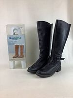 Front and side view of black leather riding boots with white boot shaper package visible.