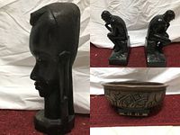 Two black statue figurines showing thinker pose alongside carved wood head and decorative wood bowl.