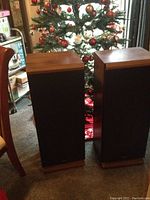 Pair of tall wooden finish Fisher speakers placed next to a decorated Christmas tree.