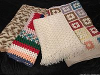 Four large crocheted afghans laid out together highlighting different colors and textures.