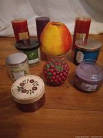 Photo of various brand new high-end scented candles arranged on wooden floor showing diversity of sizes, shapes, and colors.