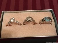 Photo showing set of three rings with different stones in a cushioned box