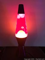 Classic lava lamp turned on, showing red liquid and white wax blobs with a silver base and cap.