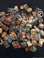 A top-down view of a large diverse collection of over 60 souvenir magnets depicting various landmarks and cultural symbols from around the world, laid out on a flat surface.