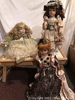 Three porcelain dolls photographed together showing dress details and facial features