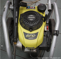 Top view of pressure washer showing yellow Honda GC190 engine with pull starter and gas cap, framed in silver metal frame with wheels.