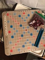 Vintage Scrabble wooden game board with letter tiles in bag and blue tile racks on top