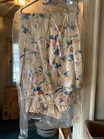 Full view of chintz fabric drapes hanging on hangers under plastic for protection