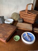 Overview of all items: picnic basket, cutting boards, tins, bowl, flower-shaped ceramic, framed ceramic wall art