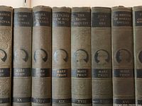 Close-up view of some volume spines showing titles, author name, and Roman numeral volume numbers for individual books in the set.