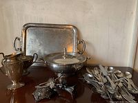 Full view showing all items including tray, pitcher, covered bowl, sugar bowl, decorative box, candle holder, and cutlery pile