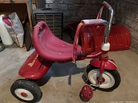 Full side view of red Radio Flyer tricycle showing plastic seat, metal frame, cargo bed, and wheels.