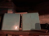 Two large robin's egg blue glazed ceramic tiles with some surface dirt visible, one showing beveled edges.