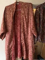 Red paisley open-front women’s jacket from Calvin Klein hanging on a white hanger