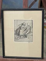 Framed black and white artwork showing mother kneeling with child, figures viewed from behind, with white mat and black frame.