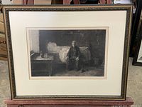 Framed etched artwork showing entire composition with seated man in rustic room.