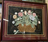 Framed oil painting showing flowers in a basket with dark background.